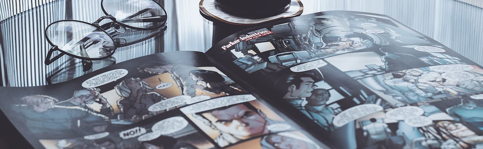 Comic abierto en mesa, lentes y café